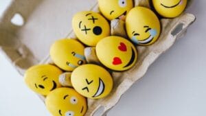 Bright yellow Easter eggs painted with emoji faces, arranged in a carton. Perfect for a festive and fun holiday theme.