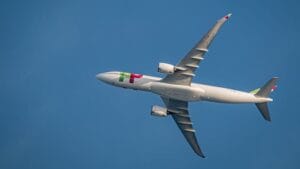 Detailed view of a commercial airplane flying overhead in clear blue sky.